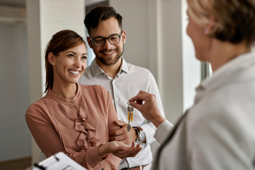 On aperçoit une femme qui donne les clés d'un bien à un couple