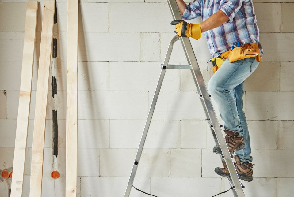 un homme monte sur une échelle sur chantier d'une maison
