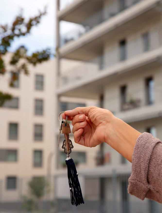 immobilier ermont france demeure Main tenant une clé d'appartement avec en fond la vue sur un appartement